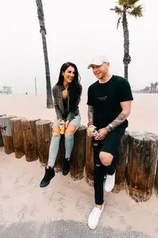 Two friends talking on the beach while sitting on wooden logs