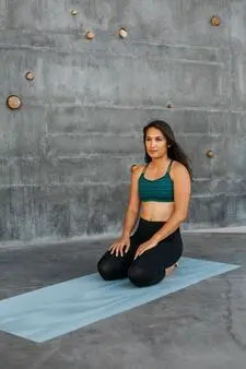 A woman wearing a sport outfit rests on the yoga mat in the rock climbing room