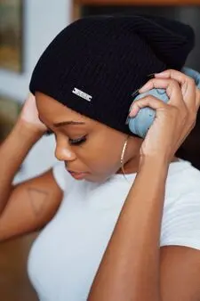 Focused woman wearing white t-shirt and black cotton hat putting on her headphones