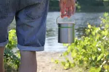 A person holding a bucket made without plastic, only steel and wood